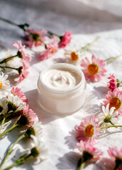 Cosmetic cream surrounded by flowers in a delicate composition