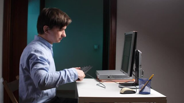 Frustrated office worker breaking keyboard at computer desk