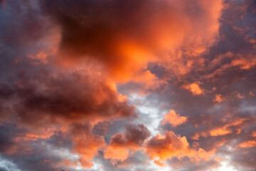 Evening sky full of clouds, illuminated by the setting sun, shining in strong orange tones
