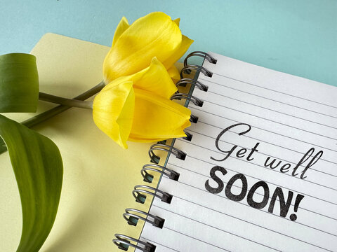 Yellow tulips on a notebook with text "Get well soon" on a pastel background