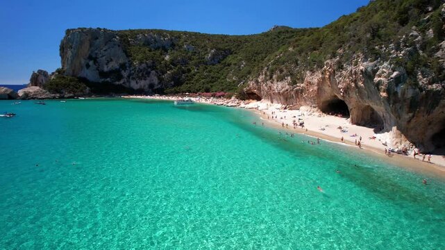 Italy, Best and most beautiful beaches of Sardegna island -  Cala Luna in gulf of Orosei . Aerial  drone view of white sandy beach , caves and turquoise sea. high angle 4khd video