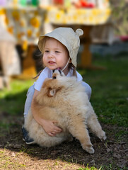 A playful little girl joyfully embracing a fluffy dog in the beautiful nature outdoors