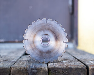 Saw wheel, Circular metal with sharp teeth wheel is resting on the wood.