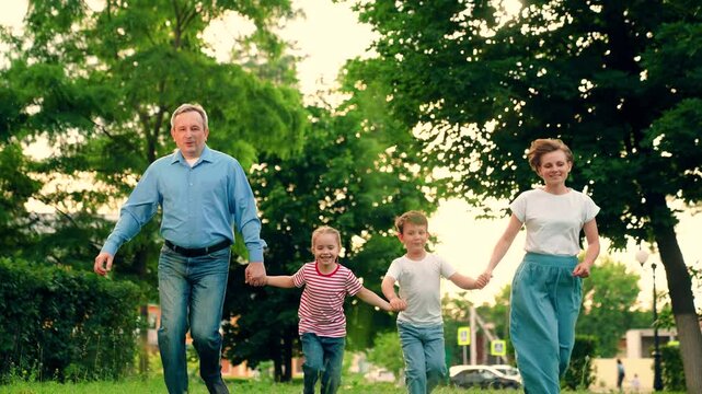 Children and parents run together on green grass. Family game, father mother daughter son fun running in park. Happy family team. Children dream, mom dad children in nature. Weekend play, holiday kids