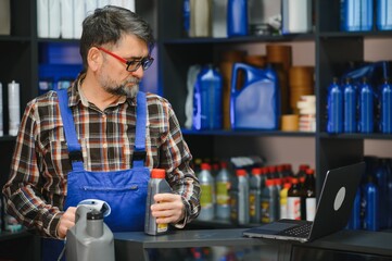 Salesman holding motor oil bottle and using barcode scanner in auto parts store