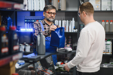 Salesman showing motor oil to customer in auto parts store