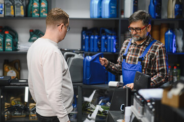 Salesman showing motor oil to customer in auto parts store