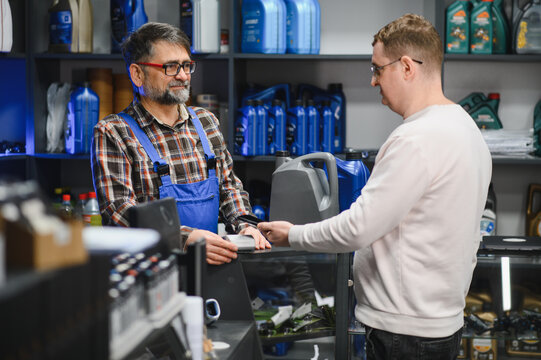 Salesman accepting payment from customer buying motor oil in auto parts store