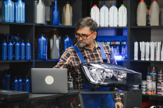 Auto parts store salesman checking car headlight information on laptop