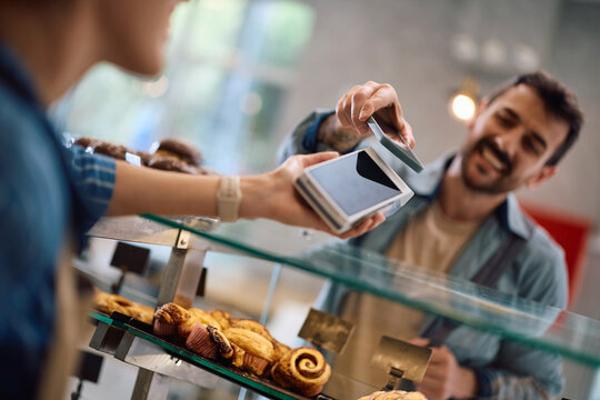 Close up of bakery customer paying with smart phone.