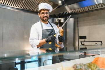 Chef sharpening knives getting ready to prepare shawarma or kebab in restaurant kitchen