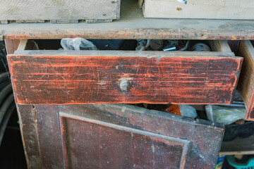 Old wooden cabinet with an open, cluttered drawer, Rustic furniture with open door.
