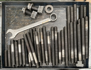 a metal cage with steel threaded bolts or studs, flanges and nuts and a number 32 open-end wrench