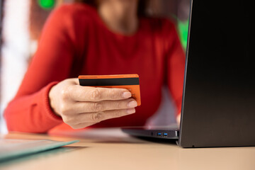 Mature woman filling her taxes documentation online and approving money transaction online, doing finances at the home office. Adult entering numbers on laptop and organizing her forms.