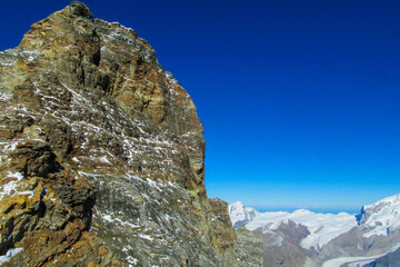 Alps mountains panoramic view in Matterhorn area. Beautiful rocky peaks, mount and gray stones on a sunny day, deep blue sky with clouds. Alps snow mountains Monte Cervino and Monte Rosa range summits