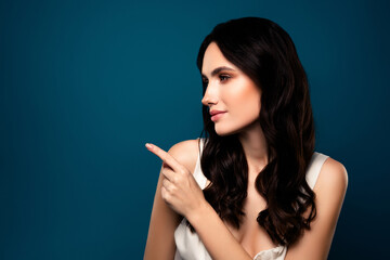 Fototapeta premium Stunning young brunette woman pointing to the side against a gradient blue background
