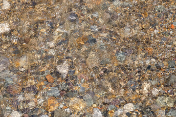 Abstract textured background of beach pebbles submerged in water.Copy space for text.For graphic design,banner background and 3D rendering