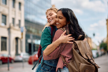 Cheerful female students embracing while greeting at campus. © Drazen