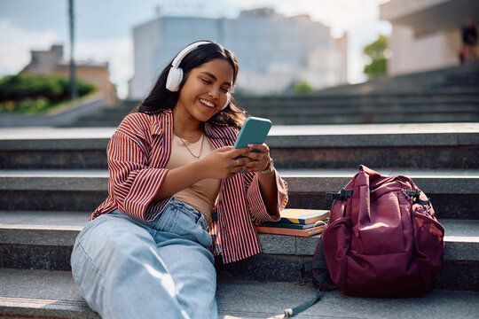 Happy Indian student using her smart phone at university campus.