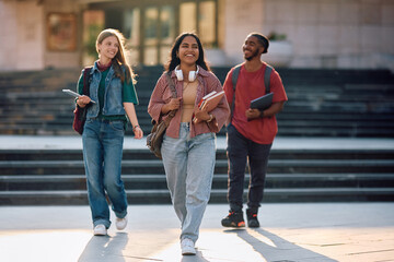 Multiracial group of happy students walking through university campus.