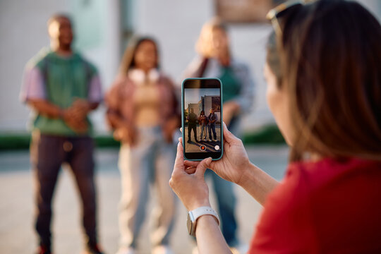 Close up of student filming her friends with smart phone at university campus.
