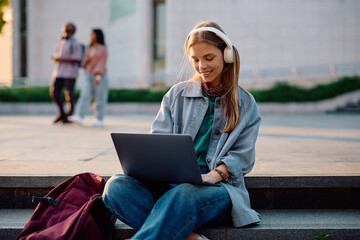 Happy female student surfing the net on laptop at university campus.