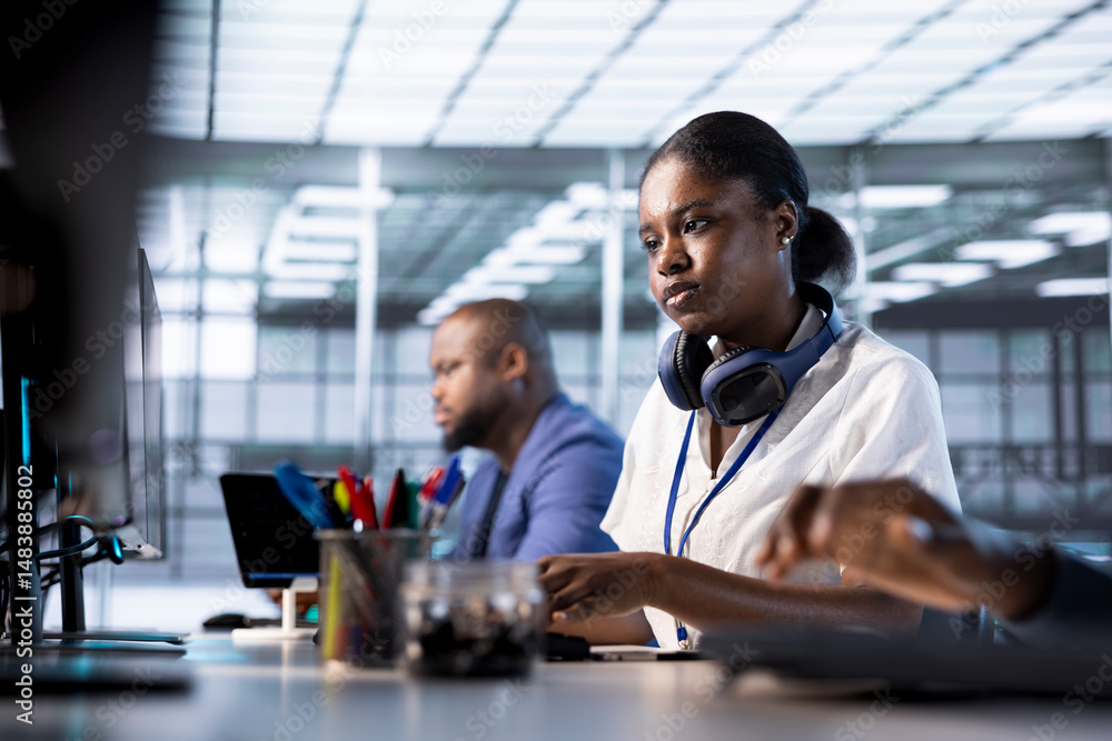 Poster african american engineer next to coworkers in server farm checking recovery plan, monitoring data c
