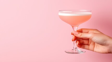 Pink Cocktail Held In A Hand Against A Pink Background