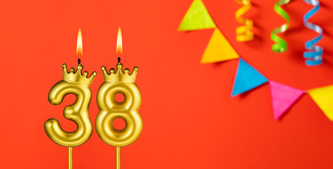 Number 38 birthday candle on an orange background with pennants