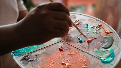 Talented artist using modern tools and painting supplies to create an artwork, mixing watercolors...