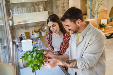 man examining home plant and woman use tablet in the kitchen