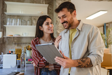 happy couple stand in the kitchen and use digital tablet together
