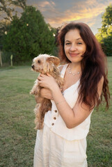 A woman is holding a dog in a park