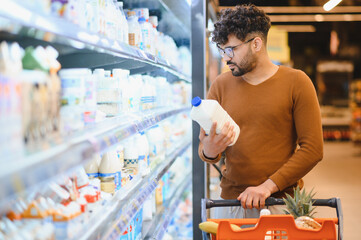 Customer choosing milk bottle in supermarket dairy section