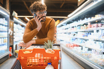 Arab man talking on phone while shopping for groceries in supermarket