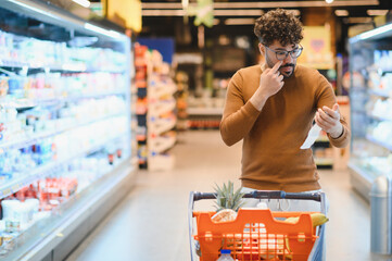 Customer checking receipt and touching his nose in supermarket while shopping for groceries