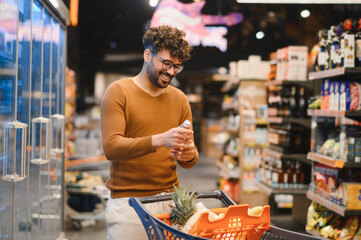 Smiling arab man choosing bottled water in supermarket