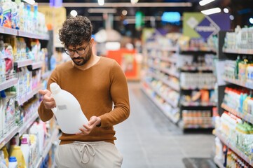 Customer choosing cleaning product in supermarket aisle