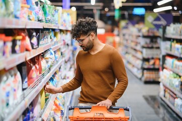 Arab customer choosing groceries in supermarket with shopping cart