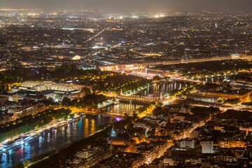 Fototapeta premium Panoramic Night View of Paris Skyline with Eiffel Tower, Illuminated Cityscape, and Montparnasse Tower Seen from a High Vantage Point during a Clear Evening