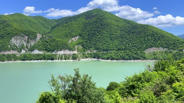 The Zhinvali reservoir, the lake landscape with mountains, the main Caucasian ridge, the Georgian military road. Georgia. An artificial reservoir. Blue sky with white clouds. 4К