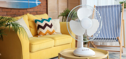 Electric fan on wooden coffee table in interior of stylish living room