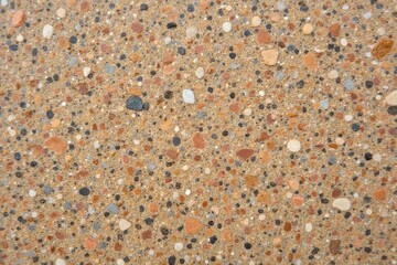 Textured concrete surface with pebbles and stones in earthy tones  