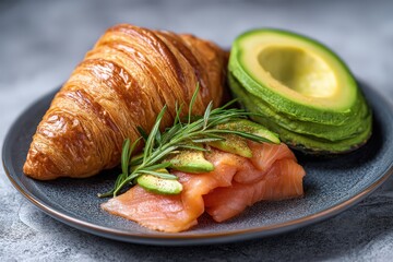 Delicious breakfast with croissant, salmon, and avocado.