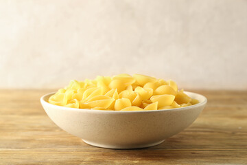 Bowl with raw conchiglie pasta on table
