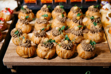 Savory Cream Puffs with Mushroom Mousse and Garnish. Elegant canapé selection featuring golden choux puffs filled with savory mushroom mousse, topped with hazelnuts and microgreens.