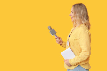 Portrait of female journalist with microphone and notebook taking interview on orange background