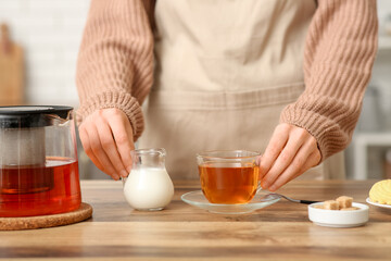 Young woman making tea with milk in kitchen