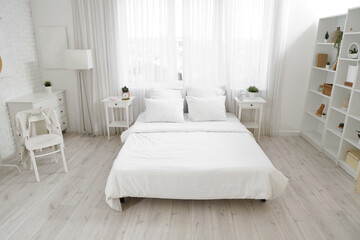 Interior of light bedroom with tables and window