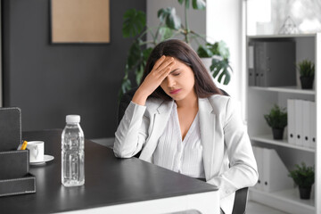 Young woman suffering from headache sitting in office